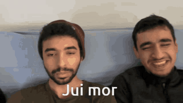 two men are sitting next to each other and one of them says " jui mor " in white
