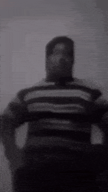 a black and white photo of a man in a striped shirt .