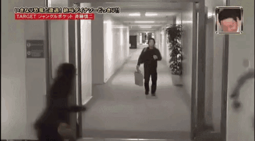a man is walking down a hallway holding a suitcase .