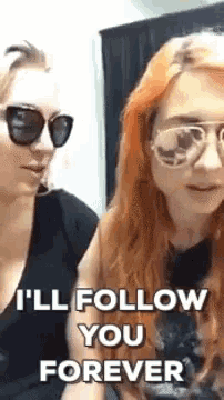 two women wearing sunglasses and a black shirt are standing next to each other .
