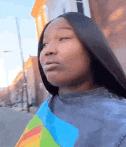 a woman with long hair is standing in front of a building and making a face .