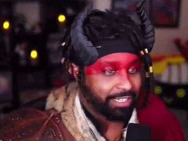 a man with a beard and red paint on his face is wearing a headband with horns on it .
