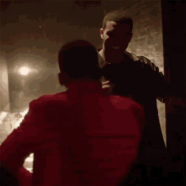 two men are standing next to each other in a dark room .