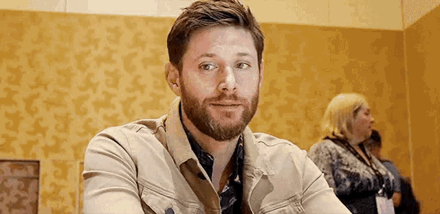 a man with a beard is sitting at a table looking at the camera .