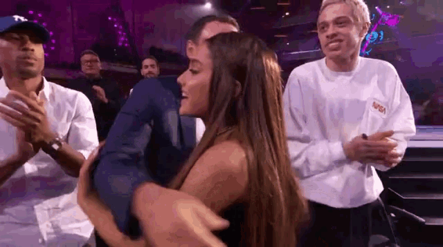 a man is holding a woman in his arms in front of a crowd of people .