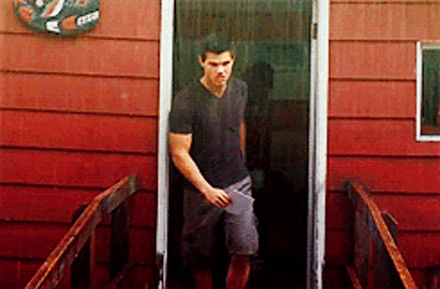 a man in a black shirt is standing in front of a red building