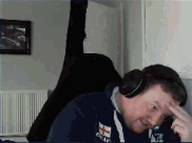 a man wearing headphones is sitting in a chair with his hand to his forehead .