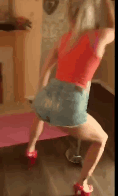 a woman in a red top and blue shorts is dancing on a yoga mat