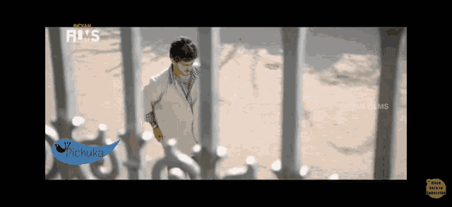 a man in a white shirt is behind a fence with a sticker that says pichuka on it