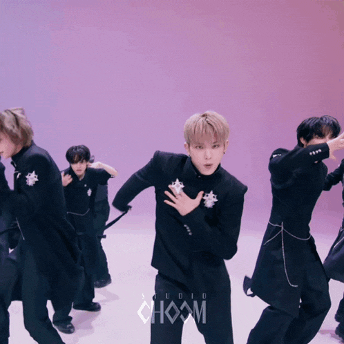 a group of young men are dancing in front of a sign that says choom studio