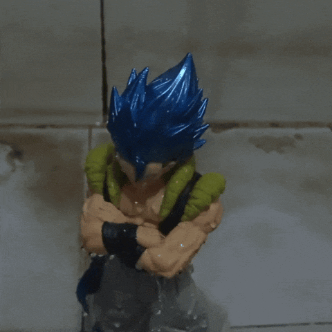 a figurine of a man with blue hair and green sleeves has his arms crossed
