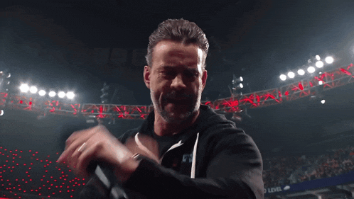 a man with a beard is singing into a microphone in a stadium