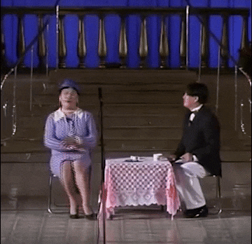 a man and a woman sit at a table on stage
