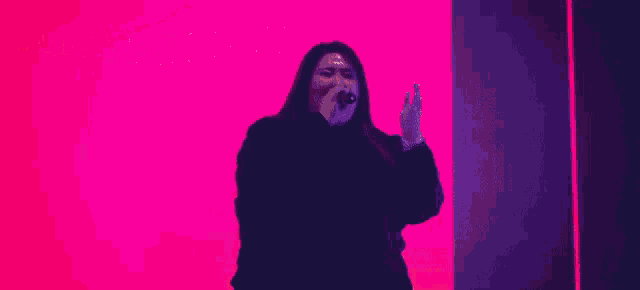 a woman singing into a microphone in front of a pink background that says la batalla de fe