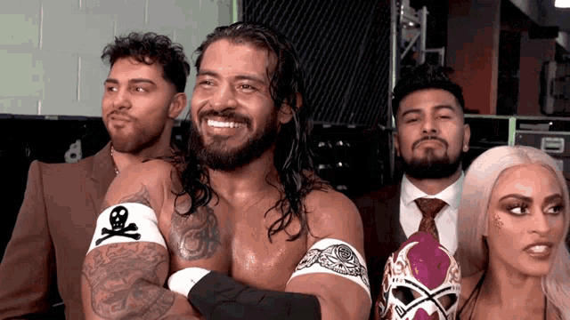 a group of wrestlers are posing for a picture with one wearing a skull and crossbones armband