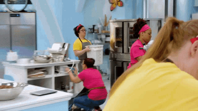 a woman in a yellow apron is holding a bucket in a kitchen