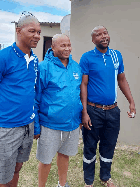 three men standing next to each other one of whom is wearing a blue shirt that says ' ambulance ' on it