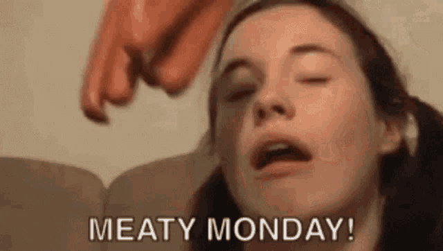 a woman is sitting on a couch with her eyes closed while a sausage is being thrown at her face .