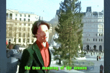 a man standing in front of a christmas tree with the words the true meaning of the season
