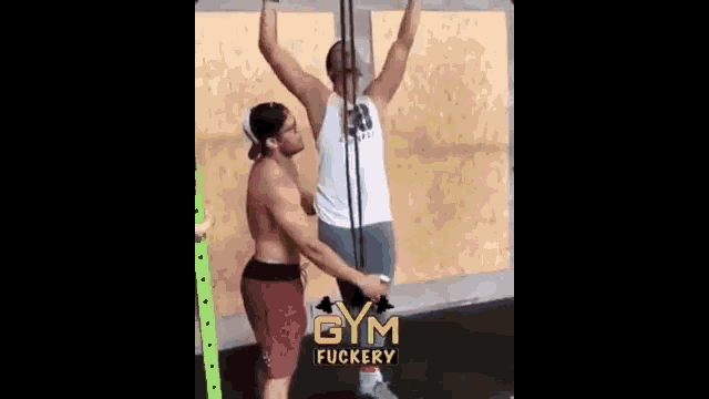 two men are doing pull ups in a gym .