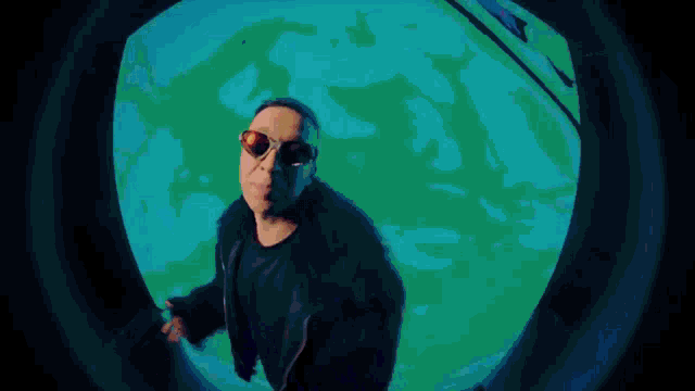 a man wearing sunglasses is standing in front of a colorful sphere