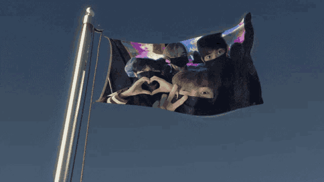 a flag with a picture of a group of people making a heart shape with their hands