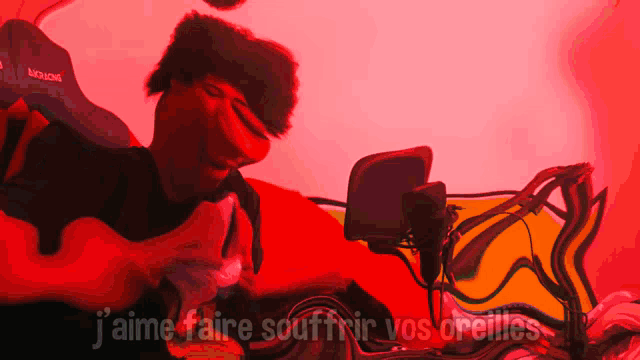a man is sitting in front of a microphone with the words " j'aime faire souffrir vos oreilles " written below him