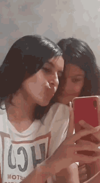 two young girls are taking a selfie with their phones .