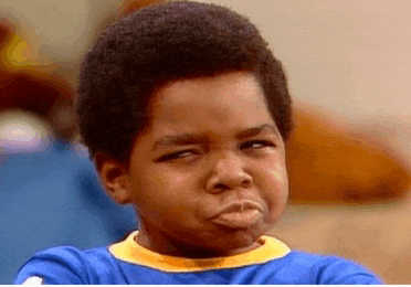 a young boy in a blue shirt is making a funny face with his arms crossed .