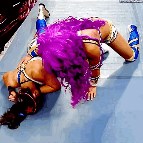 two women with purple hair are wrestling on a wrestling mat ..