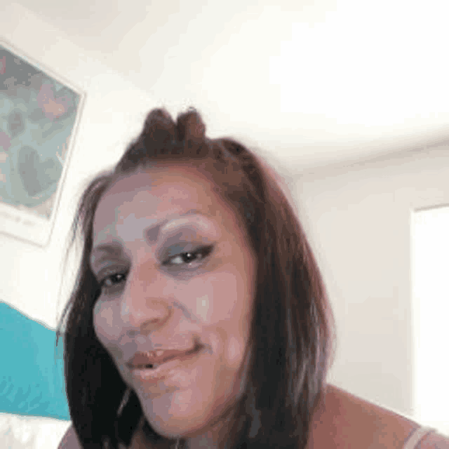a close up of a woman 's face with a picture on the wall in the background .