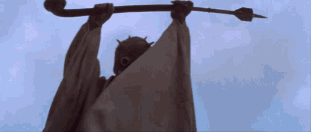 a statue of a man with a mask holding a spear