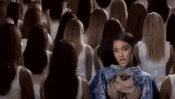 a woman in a blue jacket is standing in a crowd of people .
