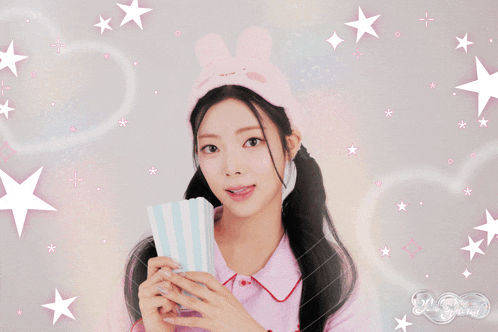 a girl wearing a headband with bunny ears holds a box of popcorn in her hands