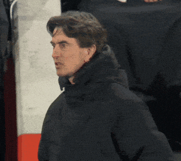 a man wearing a black jacket with a hood looks to his left
