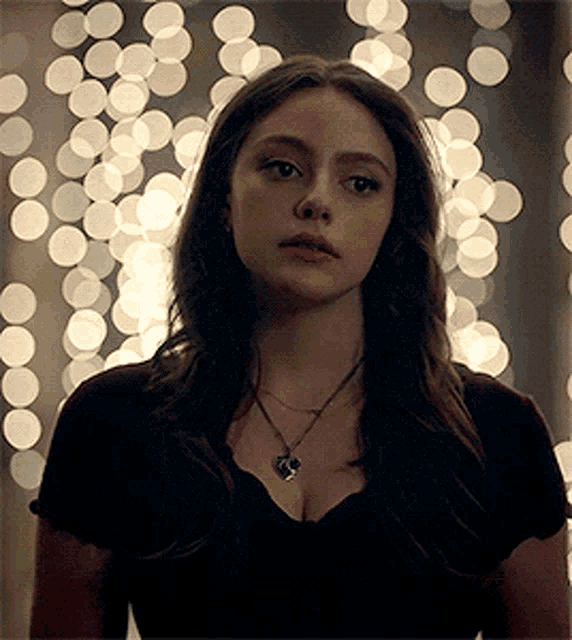 a close up of a woman wearing a necklace and a black shirt .