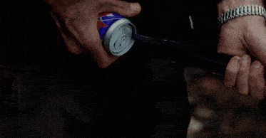 a man wearing a watch is opening a soda can with a hose