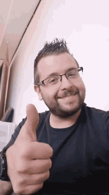 a man with glasses giving a thumbs up sign