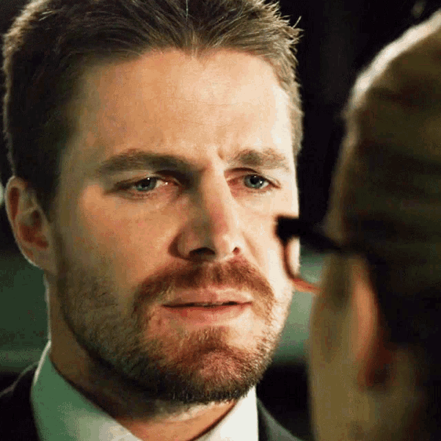 a man with a beard and glasses looks at another man
