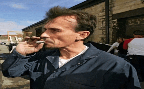 a man smoking a cigarette in front of a building that says chemist