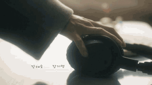 a close up of a person 's hand touching a pair of headphones with korean writing on the bottom