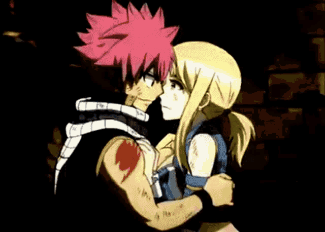 a man and a woman are hugging each other in a dark room . the man has red hair and the woman has blonde hair .