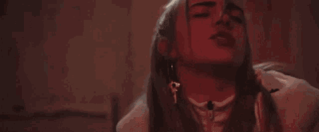 a close up of a woman 's face with her eyes closed . she is wearing a white shirt and earrings .