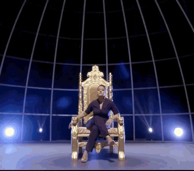 a woman in a purple suit sits on a throne