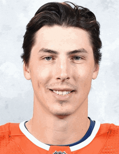 a man wearing an orange jersey with a blue and white stripe smiles