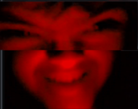 a close up of a person 's face with a red light behind them .