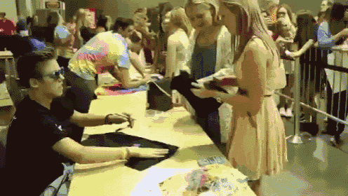 a man in a tie dye shirt signs a shirt for a woman
