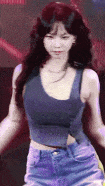a woman in a blue tank top and blue shorts is dancing on a stage .