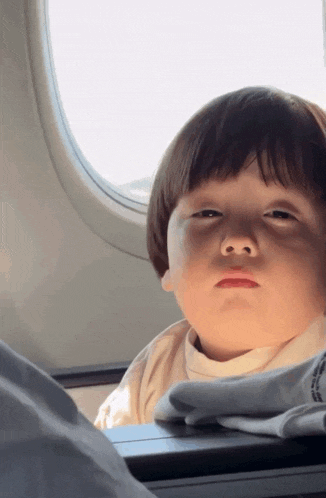 a little boy looks out of an airplane window