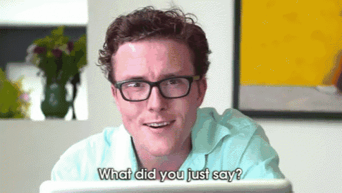 a man wearing glasses and a blue shirt is asking what did you just say